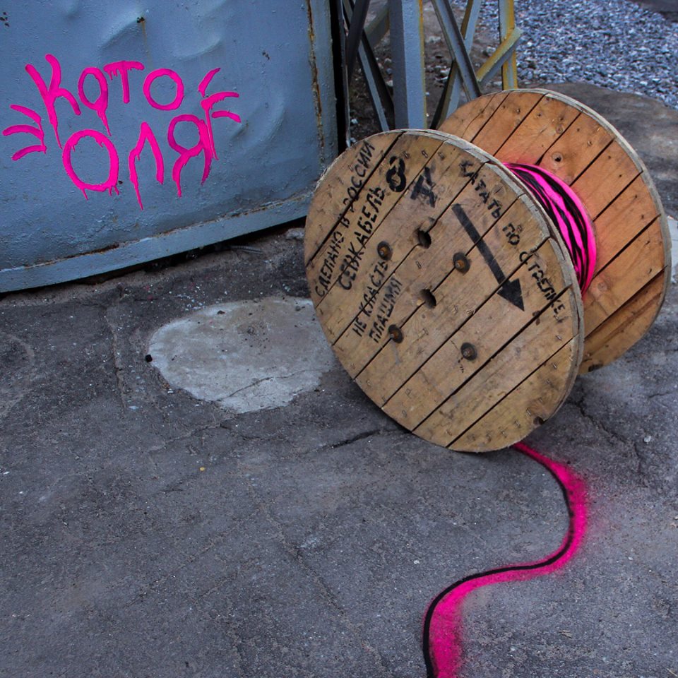 close up of one of the spools which has spraypainted pink and black lines coming off of it to look like the spools material is snaking across the ground.